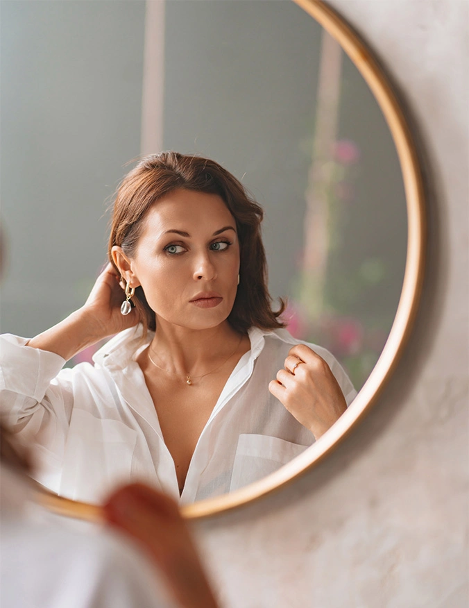 A close-up, top-down view of a man with thick, styled brown hair. The focus is on the health and density of the hair at the crown and hairline. He is wearing a white collared shirt, and the background is a neutral, out-of-focus gray. - Hair restoration in Draper, UT