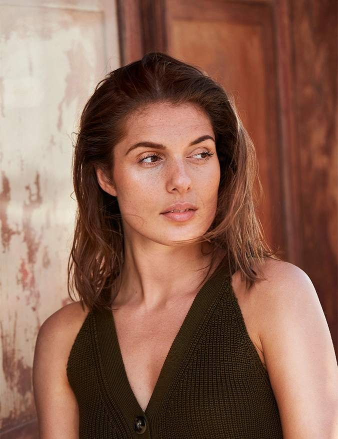 A close-up shot of a woman with her hair pulled back, looking down with a peaceful expression. She has clear, glowing skin, and the bright, natural lighting emphasizes her smooth complexion. The background is a clean, neutral white, giving the image a fresh, clinical feel. - PRP PRF therapy in Draper, UT
