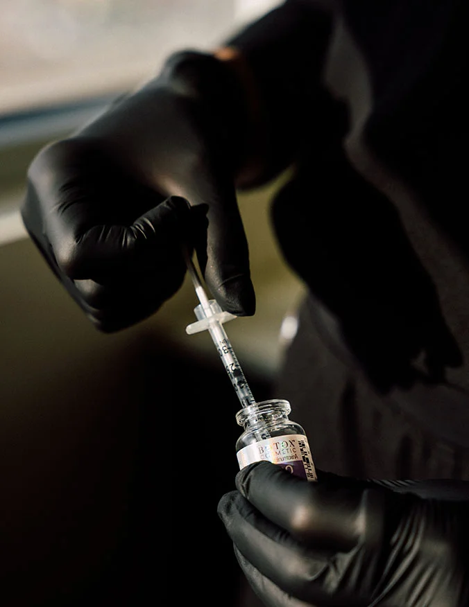 A close-up shot of a patient’s forehead and eye area as a medical professional in black gloves carefully administers a cosmetic injection using a fine-gauge syringe. - Botox and wrinkle relaxers in Draper, UT